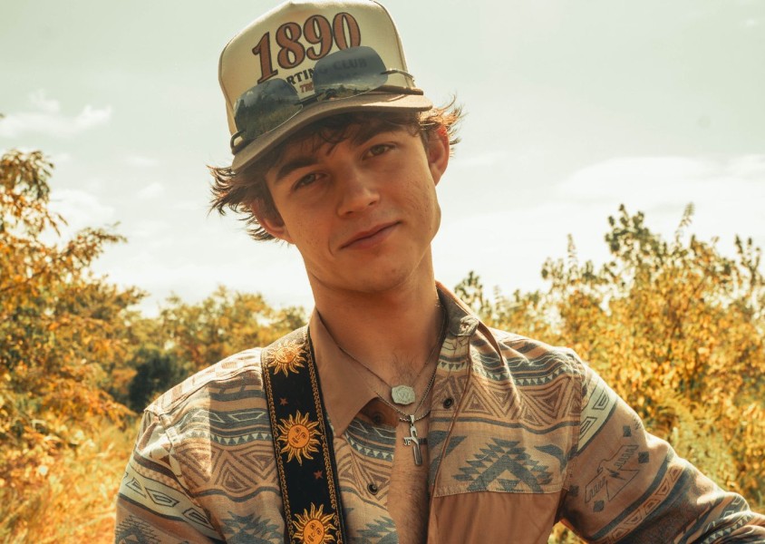 A man wearing a western printed shirt, cap, and sunglassesx
